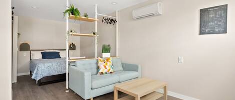 A modern living room with a light blue sofa, a wooden coffee table, and a built-in shelving unit with plants.