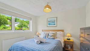 Une chambre à coucher comprenant un lit, des lampes de chevet, une commode, une fenêtre avec vue et un luminaire au plafond.