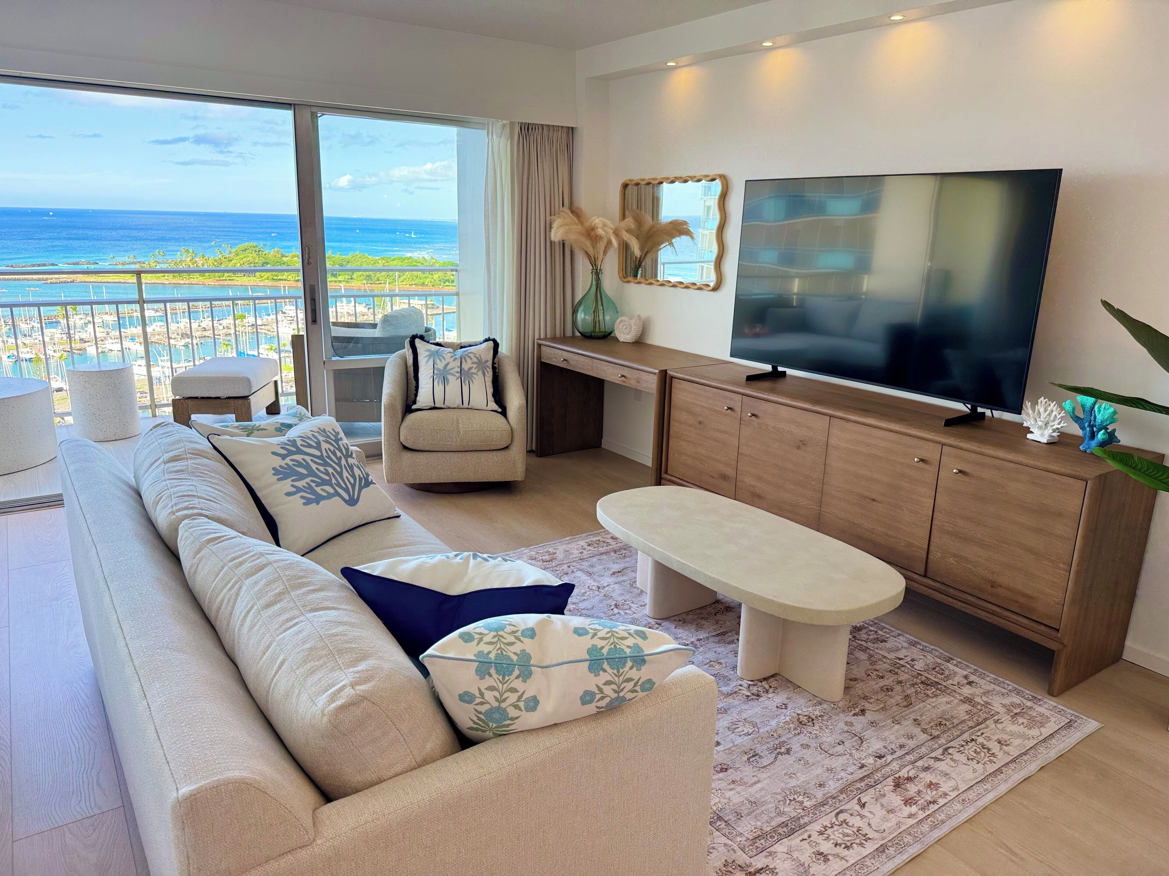 Een moderne woonkamer met een grote televisie, comfortabele zitplaatsen en uitzicht op de oceaan.