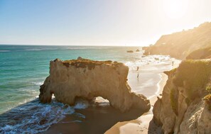 Un paysage côtier caractérisé par une formation rocheuse imposante et une plage.