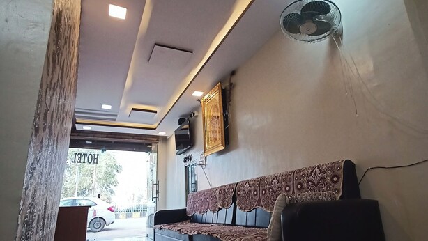 A hotel lobby with a sofa, a fan, and a sign reading "HOTEL". - Brajrani Hotel (Datia)