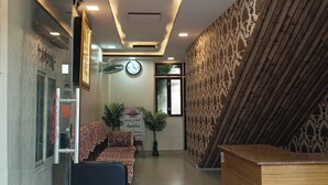 A hotel reception area with a reception desk, a clock, a sofa, and a signboard. - Brajrani Hotel (Datia)