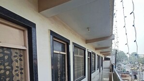 A corridor with doors, a balcony, and string lights. - Brajrani Hotel (Datia)