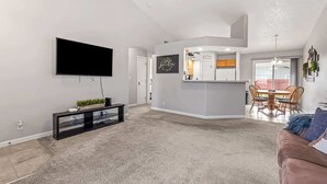 Un salon moderne avec un téléviseur à écran plat, un meuble de rangement noir et un tapis beige.