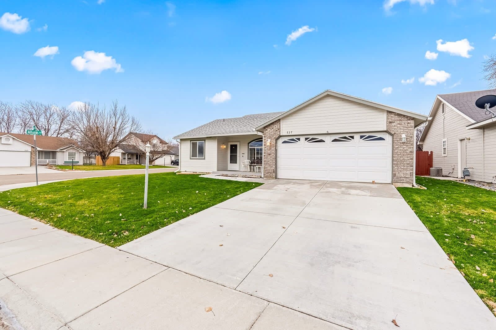A residential house with a garage, a front lawn, and a clear sky.