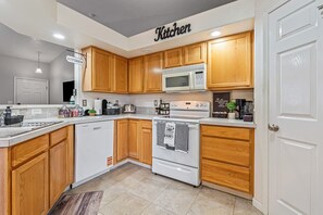 A modern kitchen with wooden cabinets, a microwave, an oven, and a dishwasher. - Cozy 3BR Nampa Home • Spacious Yard + Smart TV (Nampa)
