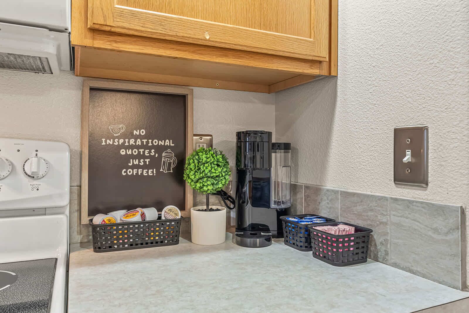 A modern kitchen with a coffee machine, a potted plant, and a wall with a motivational quote.