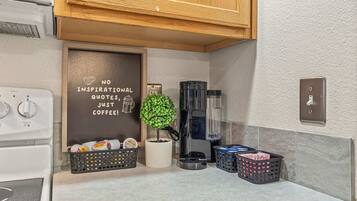A modern kitchen with a coffee machine, a potted plant, and a wall with a motivational quote.