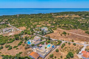 Luftaufnahme von Villa Casa Luz, mit einem zentralen Schwimmbecken, mehreren Gebäuden und einer umliegenden Landschaft mit spärlicher Vegetation.