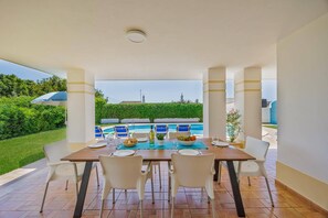 Ein Essbereich mit Blick auf einen Swimmingpool, Gartenstühle und ein Tisch für zwei Personen.
