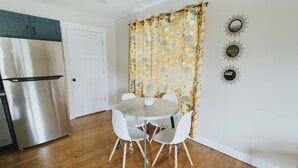 A kitchen with a stainless steel refrigerator, a white door, and a dining table with four white chairs. - Spacious & Stylish– Near Downtown Raleigh (Raleigh)
