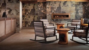 Un'area lounge moderna con poltrone a fantasia, un tavolino in legno e un camino.