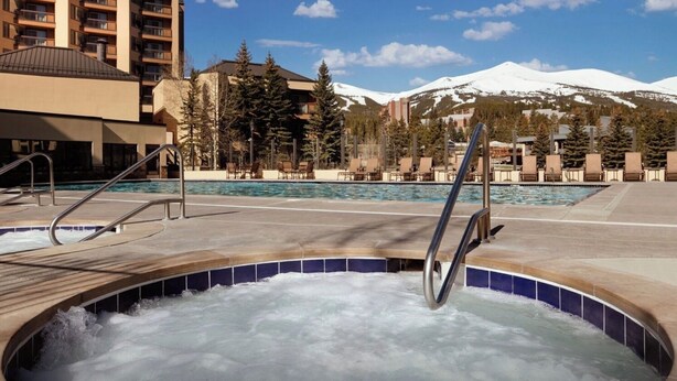 Una vasca idromassaggio con vista su una montagna e area piscina con poltrone relax.