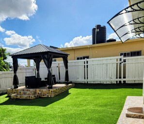 A backyard with a gazebo, a white fence, and a water tank. - Elegant 2-bedroom retreat in Montego Bay (Montego Bay)
