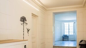 Una habitación amplia con suelo de madera de espiga, paredes blancas y una puerta que da a otra habitación.