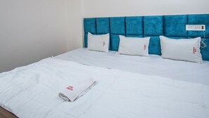 A hotel room with a bed, a ceiling fan, an air conditioning unit, and a blue headboard. - Hotel Vishwas Lok (Ujjain)