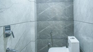 A small, modern bathroom with a toilet, a shower, and a bucket. - Hotel Vishwas Lok (Ujjain)