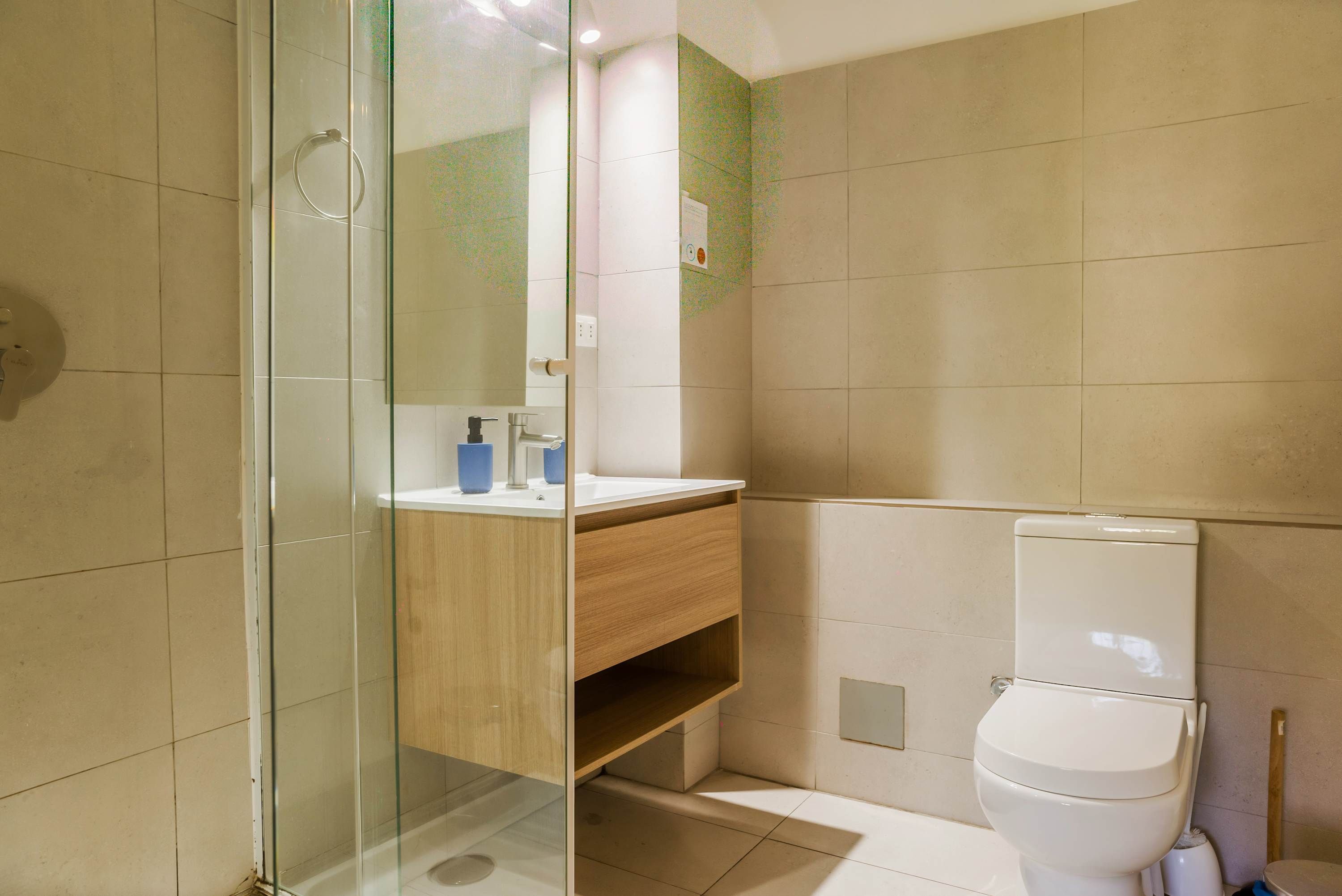 Ein modernes Badezimmer mit Duschkabine aus Glas, einem Holzwaschtisch, einer weißen Toilette und einem Spiegel.