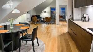 En modern lägenhet i loftstil med matplats, kök och vardagsrum.