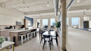 A modern kitchen with a central island, bar stools, and a dining area with a table and chairs. - Luxury 1BR Apt I King Beds I Free Parking I Gym (Dallas)