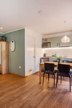 A modern kitchen with a dining area, wooden cabinets, a microwave, and a ceiling fan. - Trendy Bellavista Haven for 2 – Perfect Location! (Providencia)