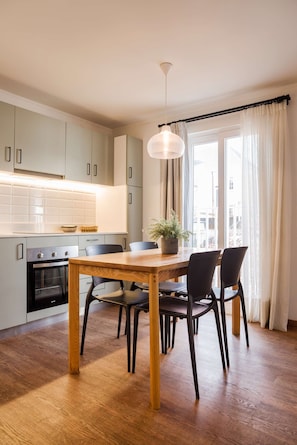 A modern kitchen with a dining table, chairs, a potted plant, and a view through a window with curtains. - Trendy Bellavista Haven for 2 – Perfect Location! (Providencia)
