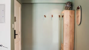 Ein Korridor mit Holzboden, einer weißen Tür und einem Holzschrank mit Spiegel.