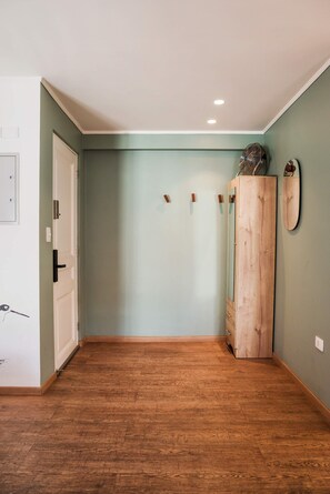 A hallway with a wooden floor, a white door, and a wooden wardrobe with a mirror. - Trendy Bellavista Haven for 2 – Perfect Location! (Providencia)
