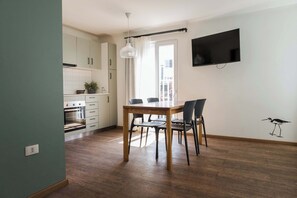 A modern kitchen with white cabinets, a dining table with chairs, and a flat-screen TV mounted on the wall. - Trendy Bellavista Haven for 2 – Perfect Location! (Providencia)