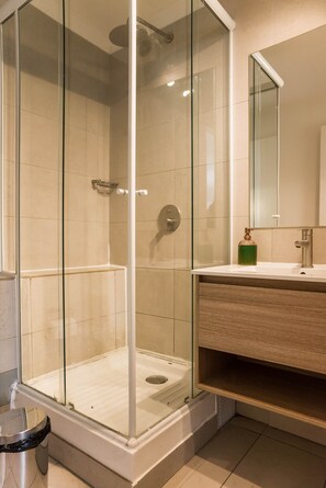 Eine begehbare Glasdusche mit Waschbecken und Spiegel darüber.