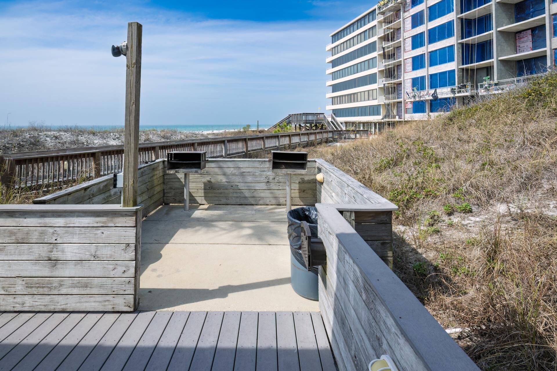 A wooden boardwalk leading to a beach with a view of the ocean and a building in the background.