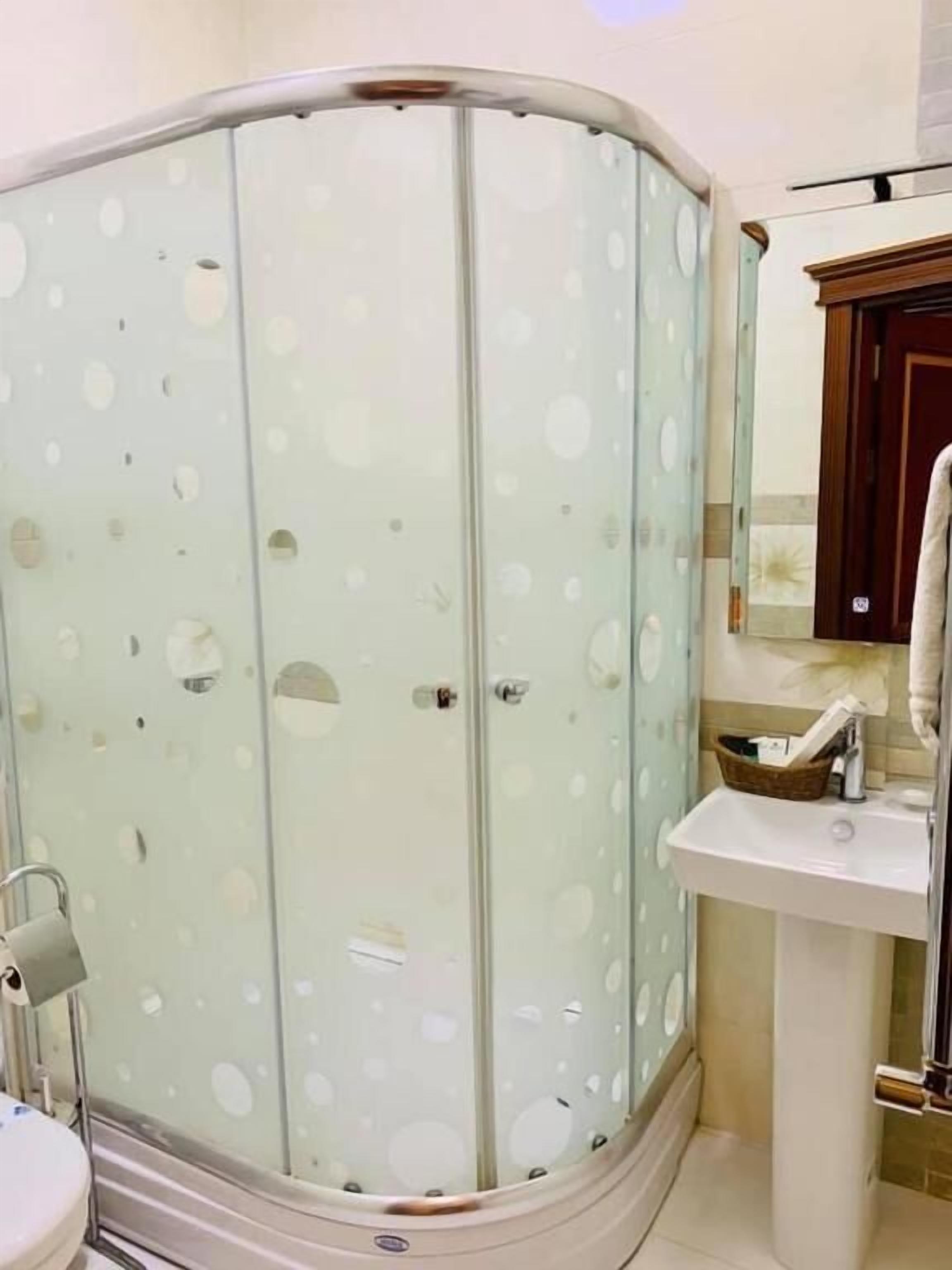 Casa de banho com cabine de duche em vidro, lavatório e espelho.