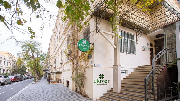 Un edificio con un letrero que dice 'Clover Boutique Hotel' y una escalera que lleva a una entrada.