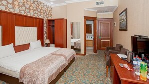 Una habitación de hotel con una cama grande, un escritorio con silla, un espejo y un televisor.