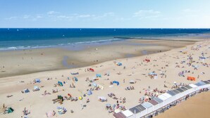 A beach with numerous sunbeds and umbrellas, a sandy shore, and a clear blue sky. - Amazing apartment in Oostende with WiFi (Oostende)