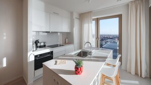 A modern kitchen with white cabinetry, a built-in oven, and a large island with a plant. - Amazing apartment in Oostende with WiFi (Oostende)