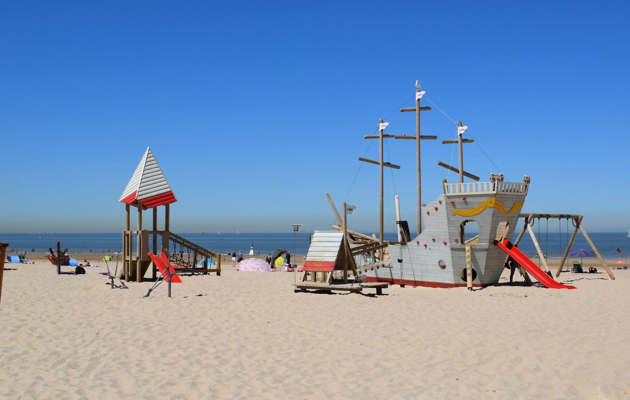 A beach with a lifeguard tower and a play structure.