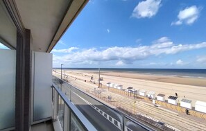 Blick vom Balkon auf einen Strand mit Bahngleis und blauem Himmel.