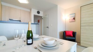 Un comedor con una mesa dispuesta para dos, una botella de vino y un cuadro en la pared.
