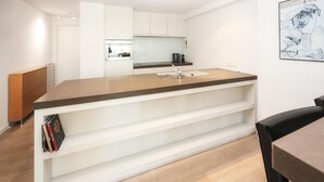 Eine moderne Küche mit weißen Schränken, einem eingebauten Backofen und einer Kaffeemaschine auf der Arbeitsfläche.