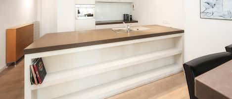 A modern kitchen with white cabinetry, a built-in oven, and a coffee maker on the countertop.