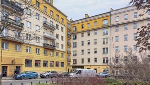 En byggnad med flera våningar, balkonger, en gata framför och parkerade bilar.