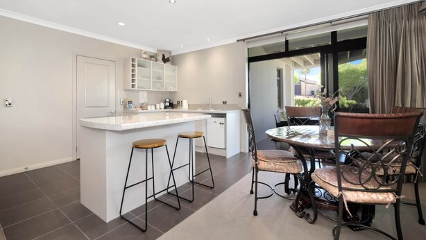 Una cocina moderna con una isla central, taburetes de bar y una mesa de comedor con sillas.
