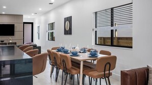 A modern dining area with a rectangular table set for six, surrounded by six brown chairs.