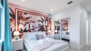 A modern bedroom with a large bed, nightstands, a mirror, and a wall mural.