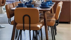 A dining area with a table set for six, surrounded by orange chairs with black frames. - Group getaway w/ soccer suites & hot tubs (Miami)