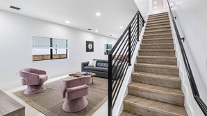 A modern living room with a staircase, a sofa, two armchairs, and a coffee table. - Group getaway w/ soccer suites & hot tubs (Miami)