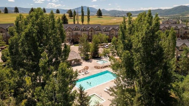 A hotel with a swimming pool surrounded by trees, a tennis court, and a view of distant mountains. - Hidden Moose Lodge MH610 | Near Snowbasin|Eden, Ut (Eden)