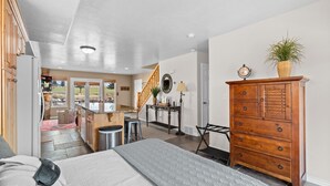 A spacious living area with a large bed, wooden dresser, and a staircase leading to a balcony. - Hidden Moose Lodge MH610 | Near Snowbasin|Eden, Ut (Eden)