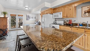 A kitchen with granite countertops, wooden cabinets, a refrigerator, microwave, stove, and a sink. - Hidden Moose Lodge MH610 | Near Snowbasin|Eden, Ut (Eden)